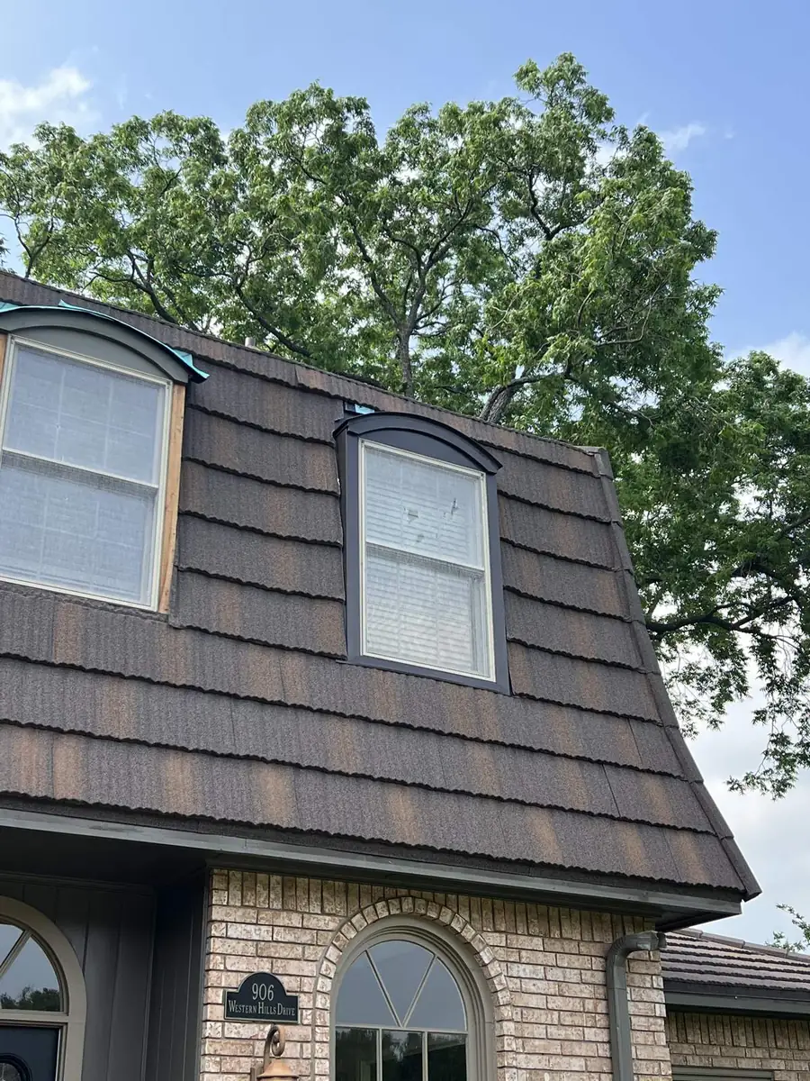 Finished stone-coated steel roof with dormers on a brick house